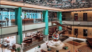 A spacious atrium with a high ceiling featuring a space-themed mural, multiple levels with seating areas, and a central circular seating arrangement.