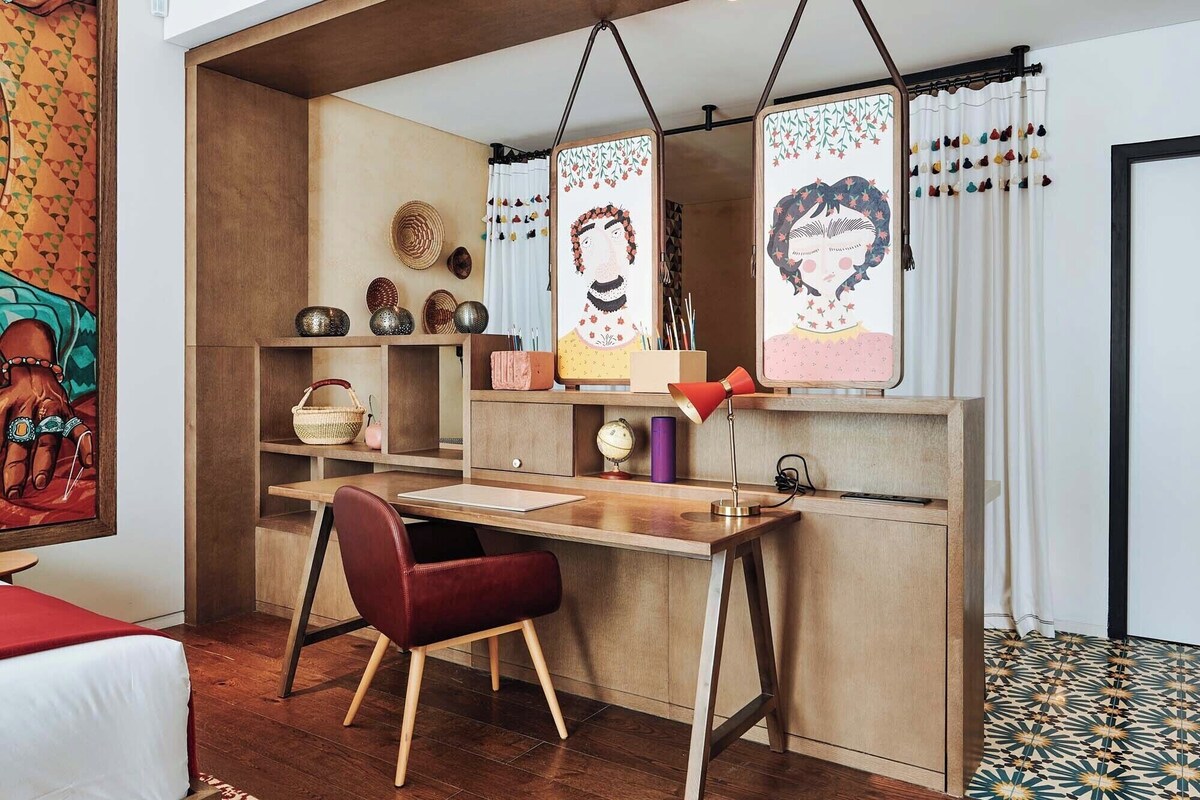 A cozy workspace with a desk, chair, and shelves with decorative items.