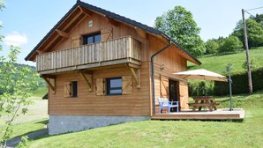A wooden chalet with a balcony, a picnic table, and a covered outdoor seating area. - Vosges mountain chalet (Ban-sur-Meurthe-Clefcy)
