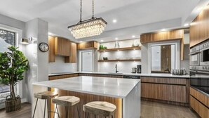 A modern kitchen with a large island, wooden cabinets, and stainless steel appliances.