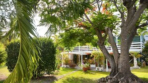Ein Garten mit einem weißen Gazebo, einem großen Baum und einem gepflegten Rasen.