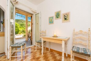A room with a wooden table, two chairs, a candle, and three framed artworks on the wall. - Effie Apartment - One Bedroom Apartment, Sleeps 2 (Corfu)