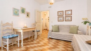 Une pièce chaleureuse avec un plancher en bois, un bureau blanc avec une chaise, un canapé à rayures agrémenté de coussins et des tableaux encadrés accrochés aux murs.