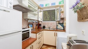 Une cuisine de taille réduite, équipée d’une cuisinière, d’un four et d’une petite fenêtre.
