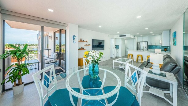 A modern living space with a balcony, a dining area, a kitchen, and a seating area with a sofa. - Waterfront 1BR condo with balcony, pool, hot tub, and resort perks in St. Petersburg. (St Petersburg)