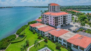 A hotel with a central building and a smaller structure on top, surrounded by a landscaped area with a view of a body of water. - Waterfront 1BR condo with balcony, pool, hot tub, and resort perks in St. Petersburg. (St Petersburg)