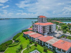 Un hotel con un edificio principale e una struttura più piccola sopra, immerso in un’area verde con vista su un corpo d'acqua.