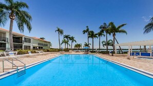 A swimming pool with lounge chairs and palm trees. - Waterfront 1BR condo with balcony, pool, hot tub, and resort perks in St. Petersburg. (St Petersburg)