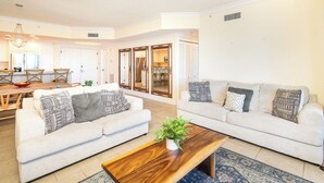 A spacious living room with two sofas, a wooden coffee table, and a ceiling fan. - Island and Sunset Views - P4-1008 (Pensacola Beach)