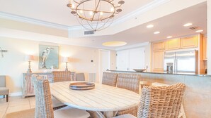 Un coin repas avec une table ronde, des chaises en osier et un lustre.