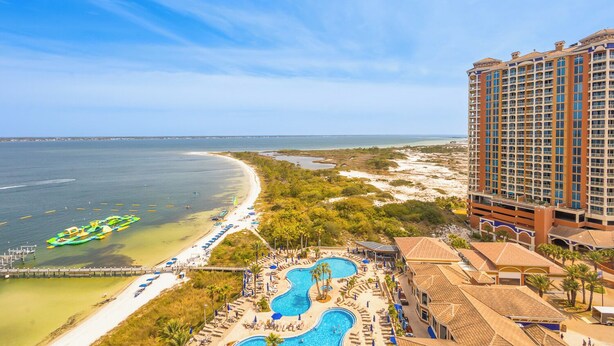 Un resort con varias piscinas, una playa y un amplio edificio de hotel.