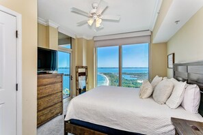 Relax in this serene bedroom with a large bed, ceiling fan, and stunning coastal views.