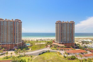 A high-rise hotel with multiple floors, a beach view, and a parking area.