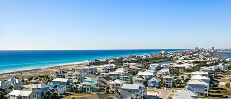 A coastal residential area with houses, a beach, and a distant city skyline.