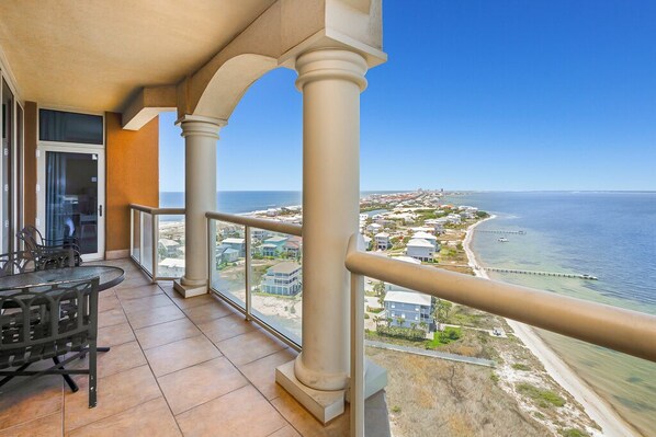 A balcony with a view of the ocean and a coastal town.