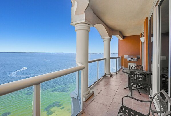 Un balcón con vista al mar, una mesa con sillas y una pequeña zona de cocina.