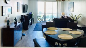 Ein modernes Wohnzimmer mit Essbereich, einem großen Fenster und einem Deckenventilator.