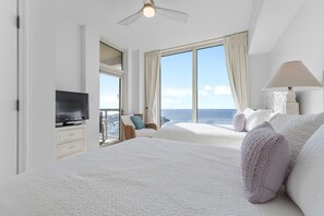 Relax in this serene ocean-view room featuring a large bed and a television on a stand.