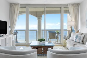 Relax in a serene space with a sofa, armchairs, and a flat-screen TV, plus a balcony with a sea view.