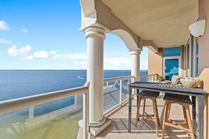 Enjoy the ocean view from this balcony with a table and two barstools.