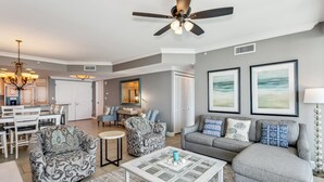 A spacious living room with a gray sofa, patterned armchairs, a coffee table, and a ceiling fan. - P5-0608 2B Gulf Front Tower 5 (Pensacola Beach)