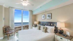 Une chambre avec un grand lit, une chaise, une table de chevet et une vue sur la plage.