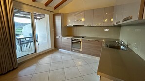 A modern kitchen with a sliding glass door leading to a balcony, stainless steel appliances, and a tiled floor. - Apartment 85m2 luxury residence sea view 6 people 2 bedrooms (Porto-Vecchio)