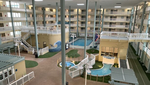 Atrio interno a più livelli con balconi, area piscina centrale e un murale con delfini.