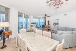 A spacious living area with a balcony, a dining table, and a sofa.