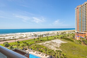 A hotel with a pool, beach view, and a parking area.