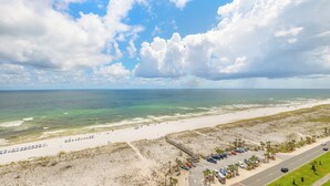 A beach with a road, parking area, and beach umbrellas.