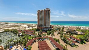 A high-rise hotel with a beach view, featuring a parking area, pool, and outdoor seating. - P2-1007 3B Gulf View Condo - Sleeps 10! Great for Families! (Pensacola Beach)