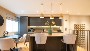 A modern kitchen with a central island, bar stools, pendant lighting, and a decorative vase. - No. 15 (York)