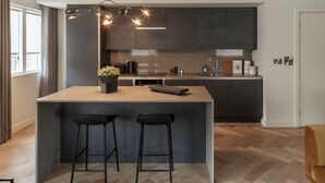 A modern kitchen with dark cabinetry, a central island with stools, and a pendant light. - No. 15 (York)