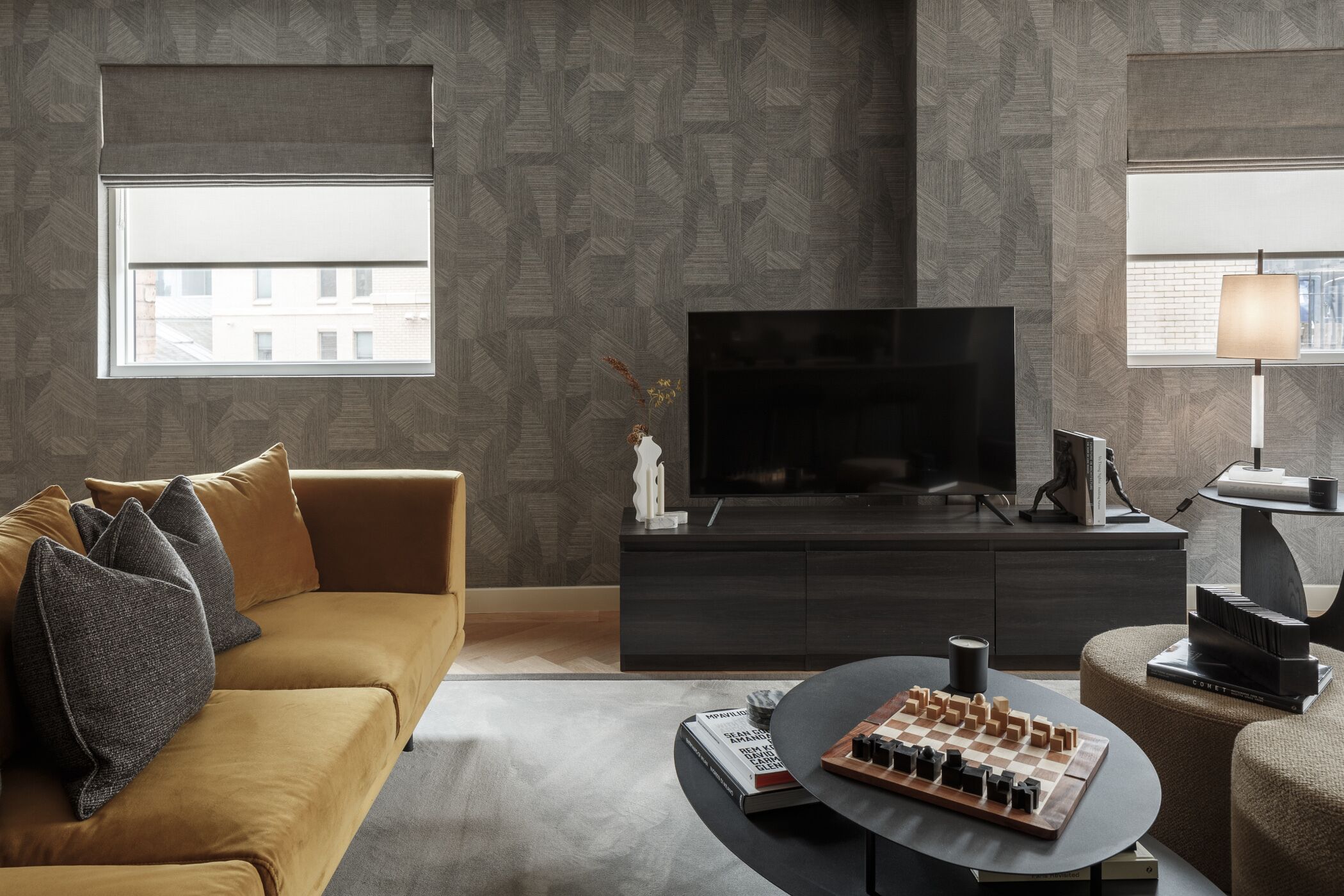 A modern living room with a sofa, a flat-screen TV, a coffee table, and a chessboard.