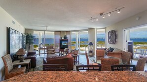 A spacious living area with a large window overlooking a body of water, furnished with sofas, chairs, and a dining table. - P3-0807*Gulf View *Tower 3* Closest Beach Access! (Pensacola Beach)