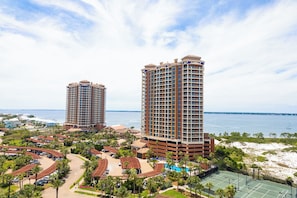 A resort with two high-rise buildings, a parking area, and a beach view.