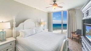 Une chambre d’hôtel avec un grand lit, un ventilateur de plafond, une télévision et une vue sur l’océan.