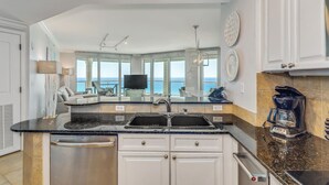 A modern kitchen with a central island, built-in dishwasher, and a coffee maker. - Gulf Front Views*Wraparound Balcony (Pensacola Beach)