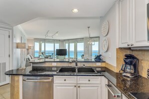 A modern kitchen with a central island, built-in dishwasher, and a coffee maker.