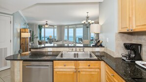 A modern kitchen with a central island, stainless steel appliances, wooden cabinets, and a view to the outside. - P3-1901 Stunning 3B Gulf Front - Wrap Around Balcony! (Pensacola Beach)