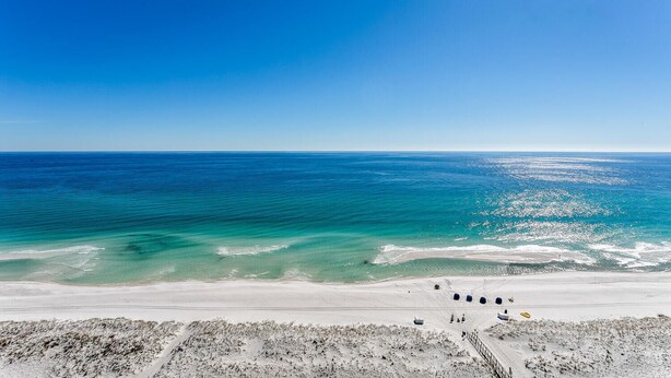 A beach with clear blue water, sandy shore, and a few beach balls.
