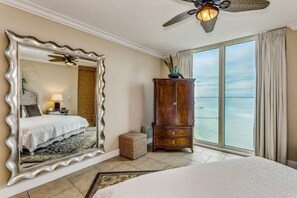 Quarto de hotel com um espelho grande, uma cama, um armário de madeira e vista para o oceano.