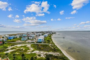 Uma área residencial costeira com casas ao longo da praia e um cais que se estende para a água.