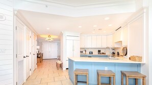 Una cocina moderna con una isla central, armarios blancos y suelo de baldosas.