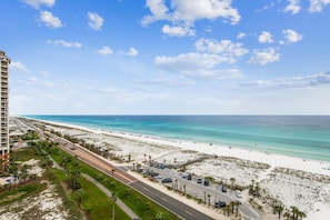 A beach with a road and a tall building in the background. - P5-1101 Newly Renovated - 3B Gulf Front @ Portofino (Pensacola Beach)