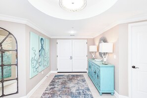 A hallway with a patterned rug, a blue cabinet, and two wall-mounted lamps.