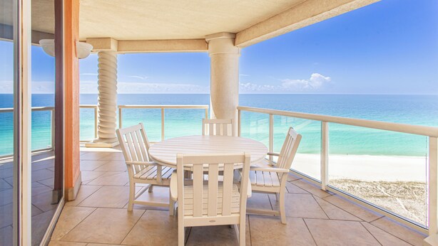 A covered outdoor seating area with a view of the ocean and beach.