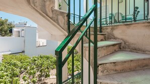 Un escalier en béton avec des rampes vertes menant à un balcon agrémenté de mobilier d’extérieur.
