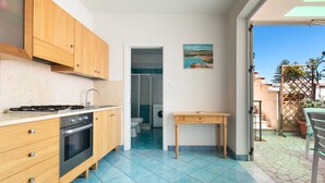 Une cuisine de taille réduite, dotée de meubles en bois, d’une cuisinière à gaz et d’un four encastré.